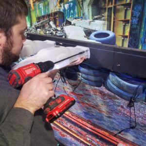 Man installing wireless charging racks for a laser tag arena.