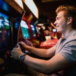 Man playing a racing arcade game with a steering wheel.
