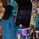 Person facing and playing an arcade game.