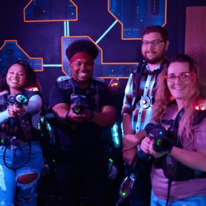 Four people wearing CyberBlast Pro laser tag gear and smiling at the camera.