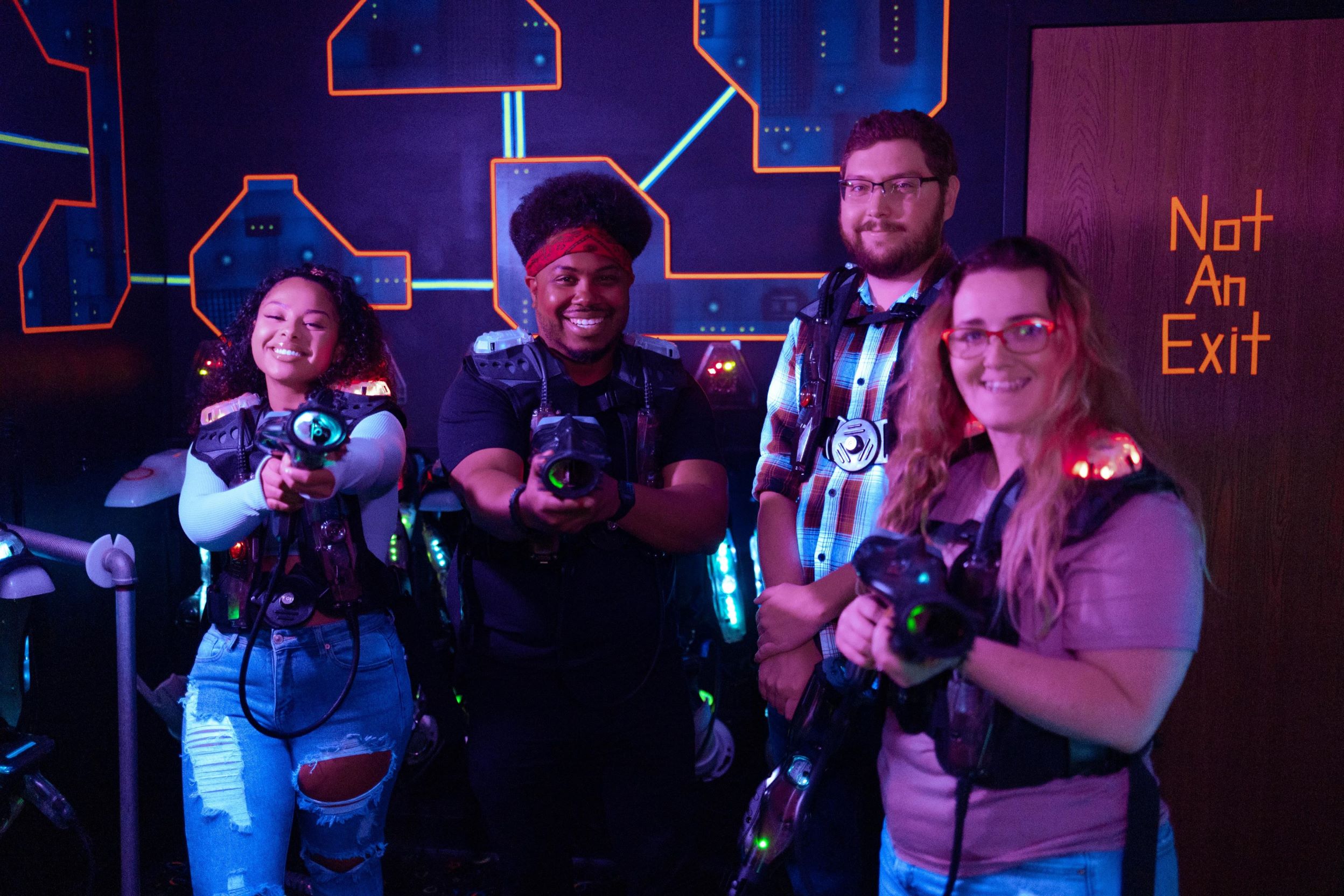 Four people wearing CyberBlast Pro laser tag gear and smiling at the camera.