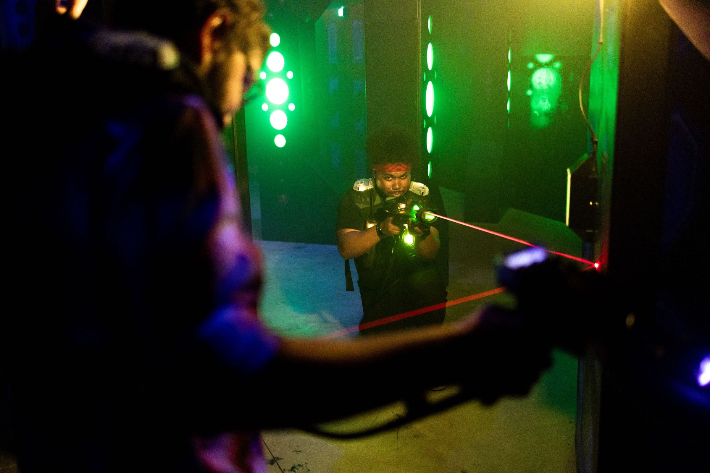 Man shooting a laser tag phaser and reflecting the laser off a mirror to tag another player