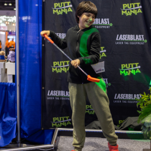 Young boy smiling and playing Putt Mania at IAAPA 2023.