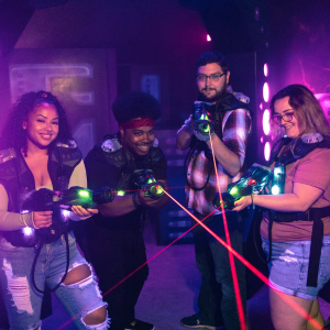 A group of four people in CyberBlast Pro laser tag equipment all pointing their red aiming lasers.