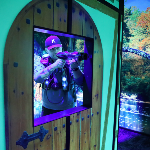 Man aiming a CyberBlast Pro laser tag phaser through an opening in a laser tag arena.