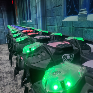 Lit up CyberBlast Pro laser tag vests hanging on vestless chargers.