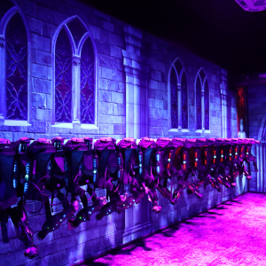 CyberBlast Pro laser tag vests hang on wireless charging racking in a black lit vesting room.
