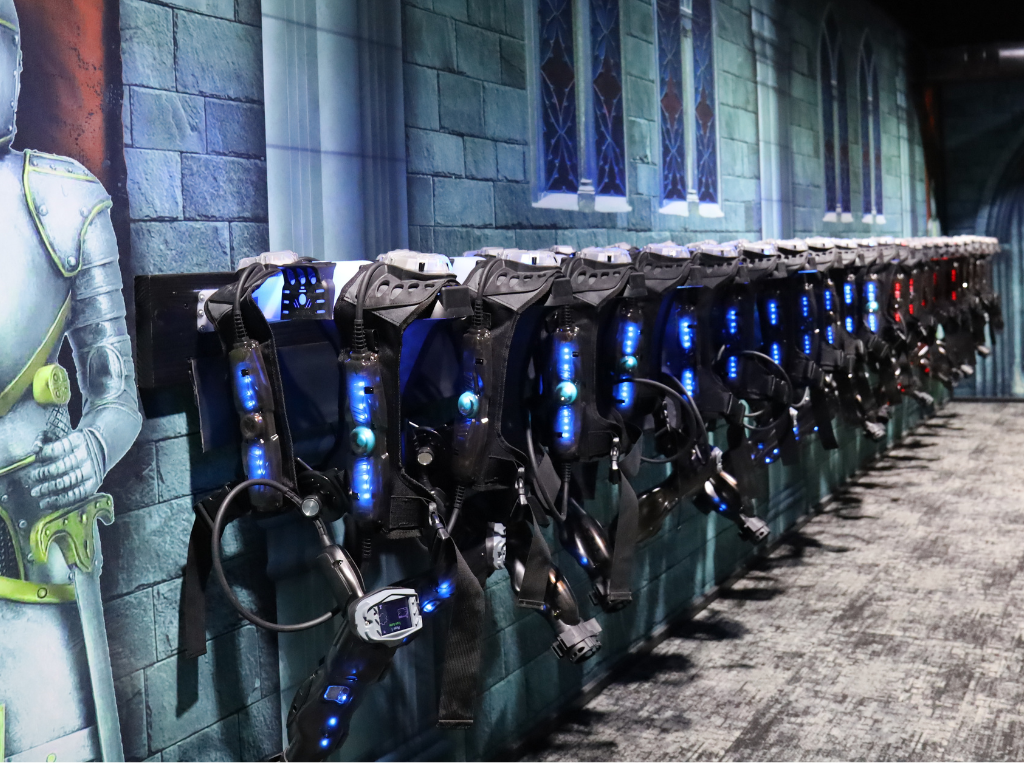 A row of LaserBlast wireless charging racks with laser tag vests and phasers hanging on them.