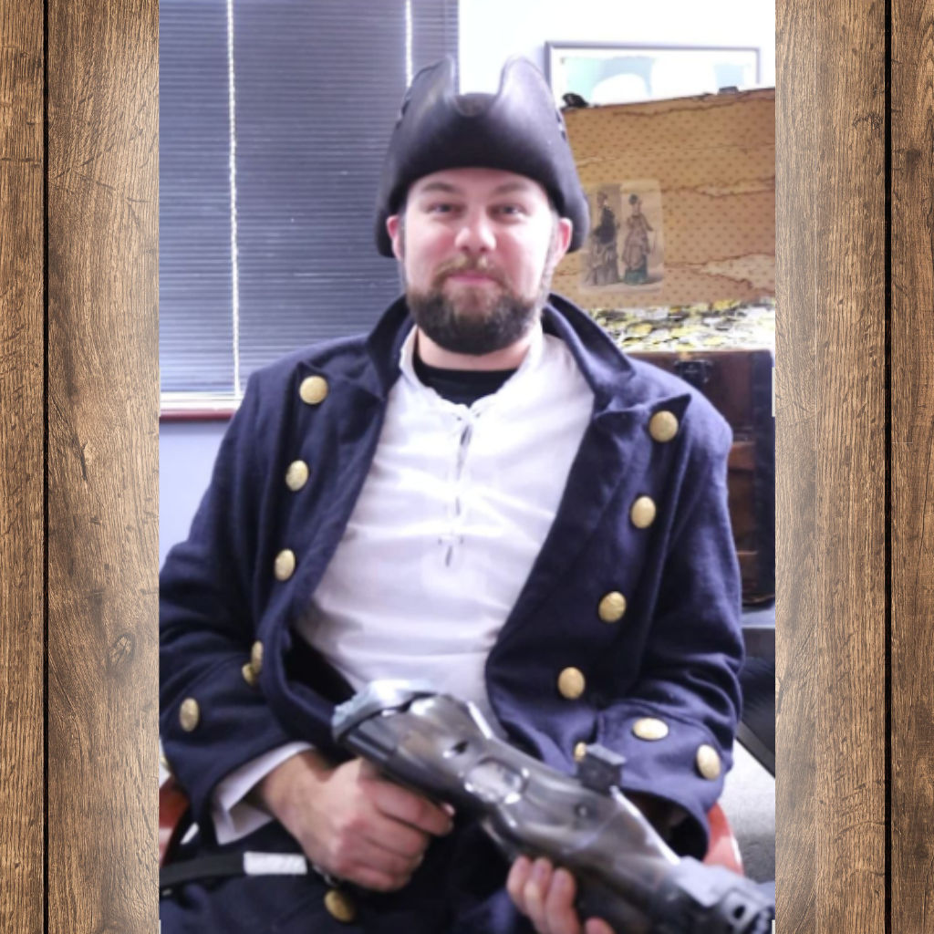 Man wearing a pirate costume and sitting in a chair with a laser tag phaser in his hand.