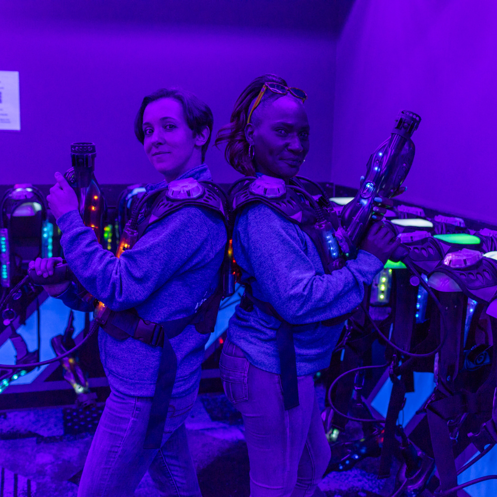 Two women in LaserBlast laser tag equipment standding back to back.