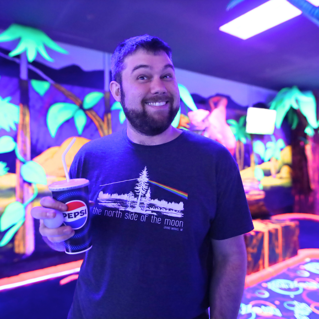 Man standing and smiling holding a Pepsi cup in his hand.