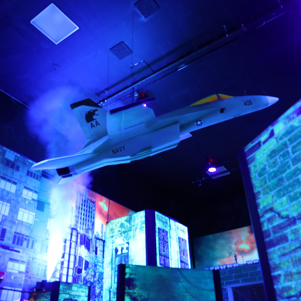 AIrplane prop on the ceiling of a laser tag arena with fog shooting up from behind it.