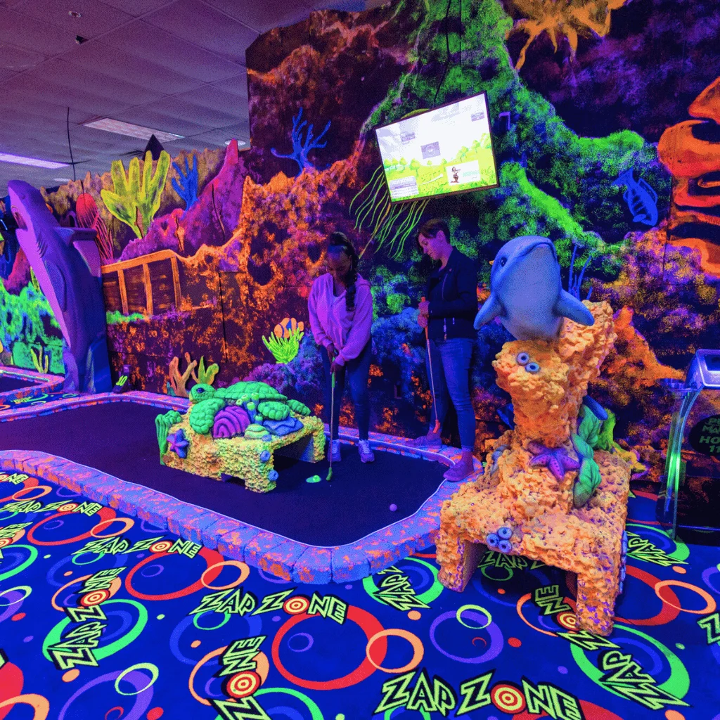 Two women putting on a mini golf course with Putt Mania mini golf tech.