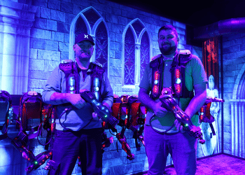 Two men wearing CyberBlast Pro laser tag equipment and looking at the screen.